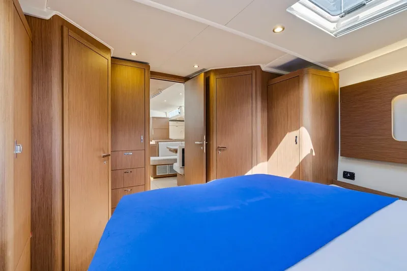 Heartbeat Yacht Photos Pics Luxurious interior of 2024 Beneteau Oceanis Yacht 54 with wood finish and blue bedding.