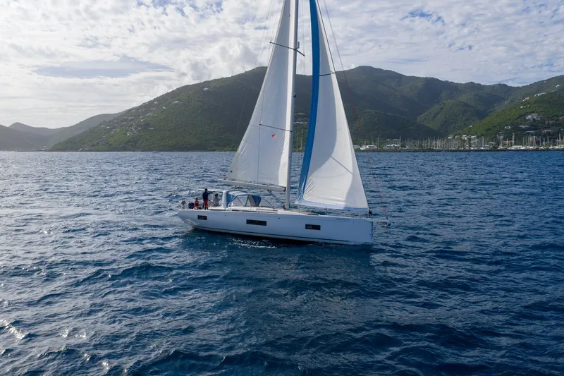 Heartbeat Yacht Photos Pics 2024 Beneteau Oceanis Yacht 54 sailing near lush green mountains.