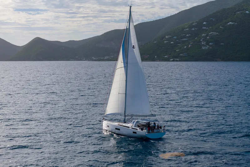 Heartbeat Yacht Photos Pics 2024 Beneteau Oceanis Yacht 54 sailing near lush green hills and calm waters.