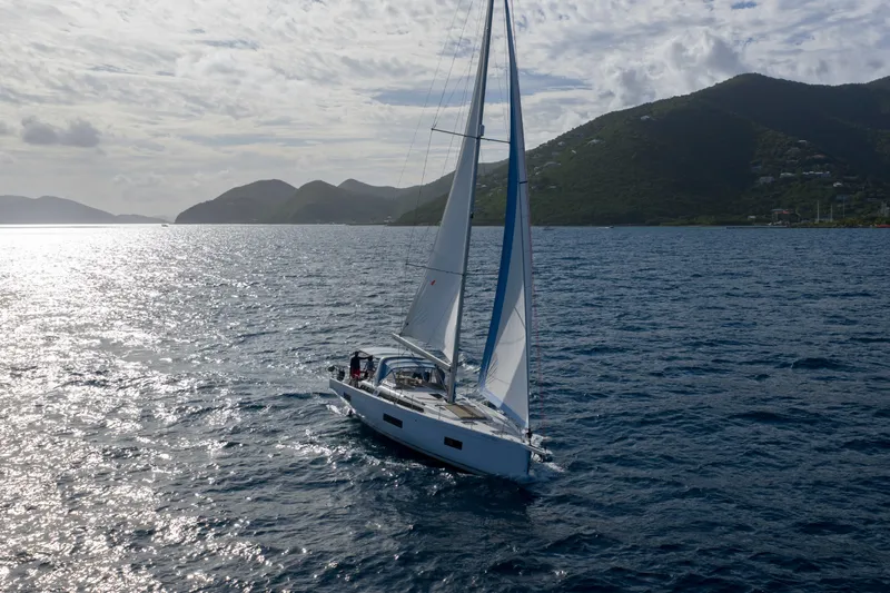 Heartbeat Yacht Photos Pics 2024 Beneteau Oceanis Yacht 54 sailing on open sea with scenic mountain backdrop.