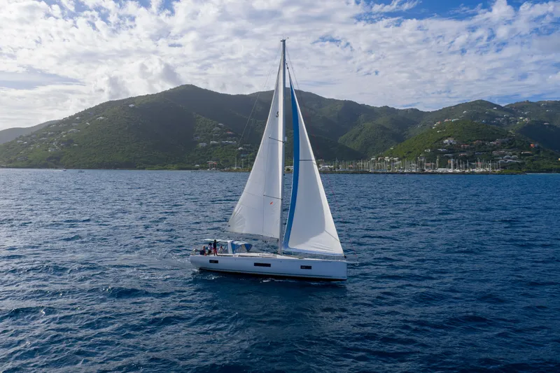 Heartbeat Yacht Photos Pics 2024 Beneteau Oceanis Yacht 54 sailing near lush green mountains.