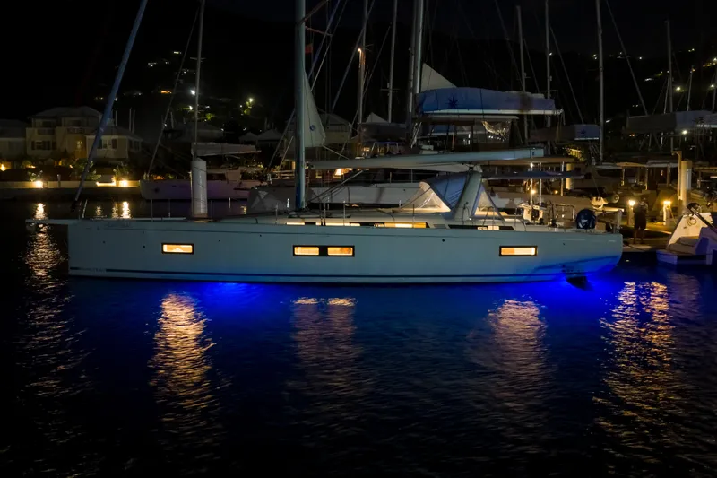 Heartbeat Yacht Photos Pics 2024 Beneteau Oceanis Yacht 54 illuminated at night in marina with blue underwater lights.