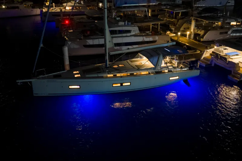 Heartbeat Yacht Photos Pics 2024 Beneteau Oceanis Yacht 54 illuminated at night in marina, showcasing blue underwater lights.