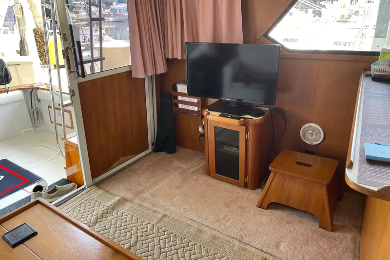  Yacht Photos Pics 1988 Chris-Craft 392 Sport Fish interior with TV, wooden furniture, and carpeted floor.