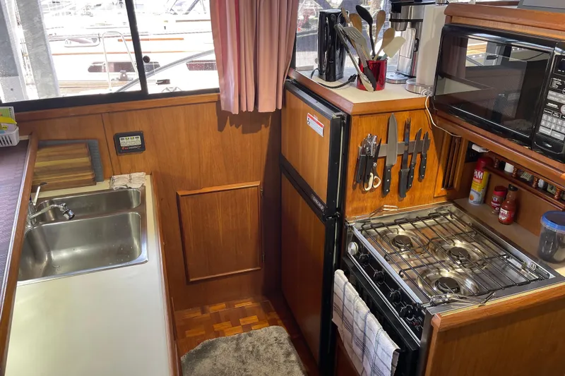  Yacht Photos Pics 1988 Chris-Craft 392 Sport Fish yacht kitchen with stove, sink, and wooden cabinetry.