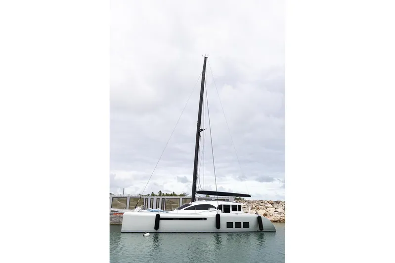 Katari Yacht Photos Pics Sleek 2018 Tag 60 catamaran docked in calm waters under cloudy skies.
