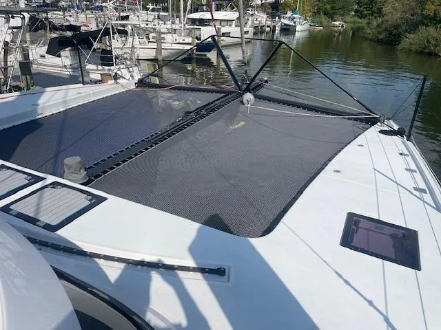 Honey Ryder Yacht Photos Pics 2022 HH Catamarans 50 docked, featuring spacious deck and netting, surrounded by other boats.