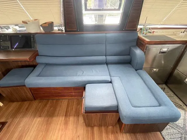 Honey Ryder Yacht Photos Pics Luxurious interior of 2022 HH Catamarans 50 with blue L-shaped sofa and wooden flooring.