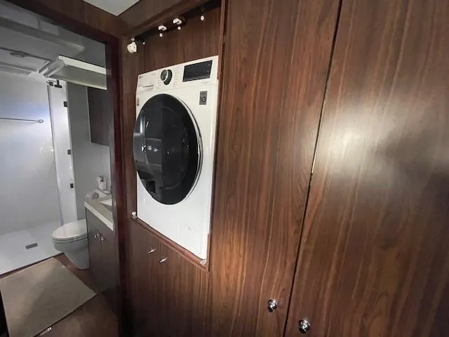 Honey Ryder Yacht Photos Pics Laundry area with washer in 2022 HH Catamarans 50, featuring wood paneling and adjacent bathroom.