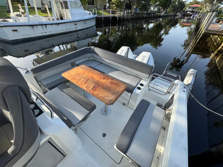  Yacht Photos Pics 2020 Jeanneau Leader 9.0 WA boat with seating area and wooden table on a calm waterway.