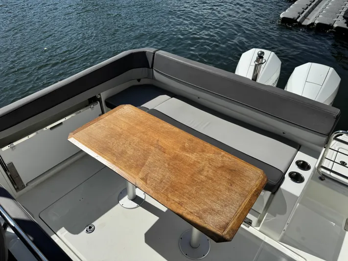 Yacht Photos Pics Jeanneau Leader 9.0 WA 2020 boat with wooden table and seating, docked by the water.