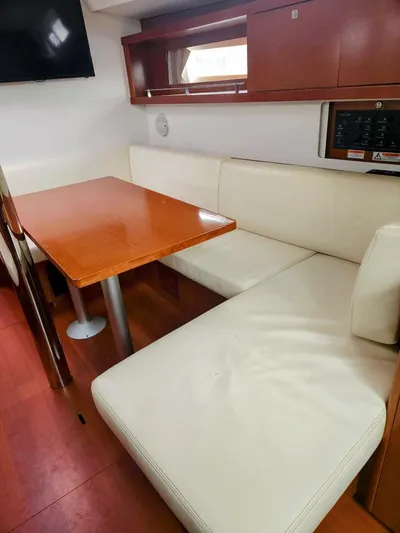 Far Star Yacht Photos Pics Interior of 2012 Beneteau Oceanis 41 yacht with white seating and wooden table.