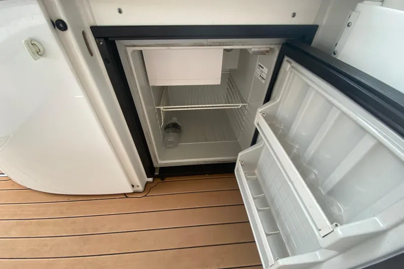  Yacht Photos Pics Open mini fridge on 2004 Formula 370ss boat, showing empty shelves and a single water bottle.