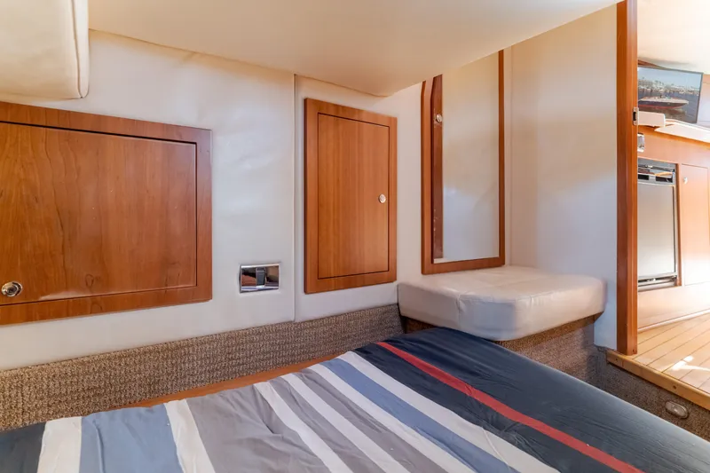 Dream Chaser Yacht Photos Pics Interior cabin of 2006 Chris-Craft Corsair 36 with wood paneling and striped bedding.