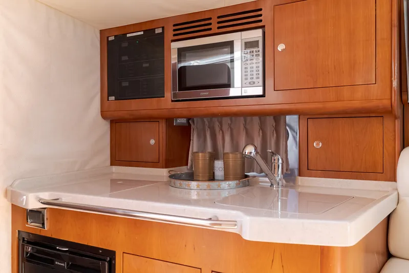 Dream Chaser Yacht Photos Pics 2006 Chris-Craft Corsair 36 interior kitchen with microwave, sink, and wooden cabinetry.