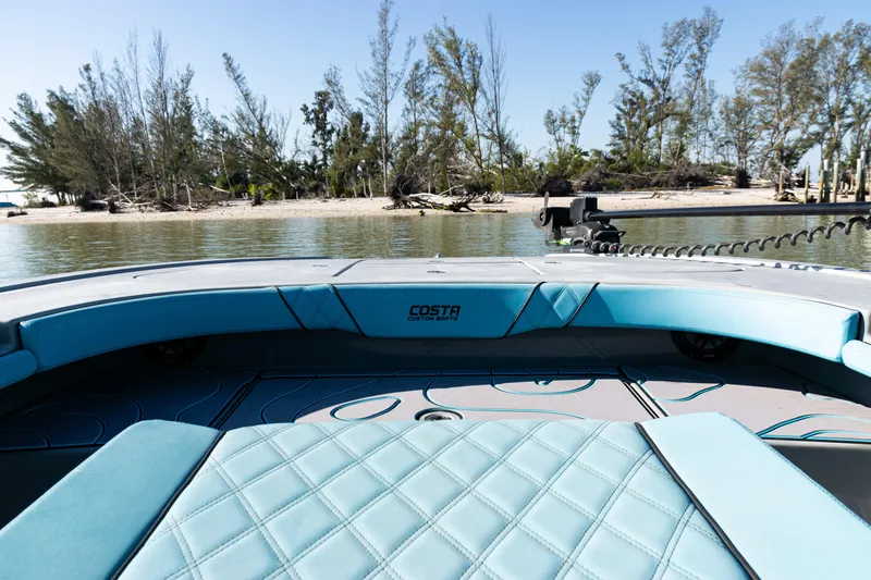  Yacht Photos Pics 2022 Costa Custom Boats 264 interior with turquoise seating, near a scenic shoreline.