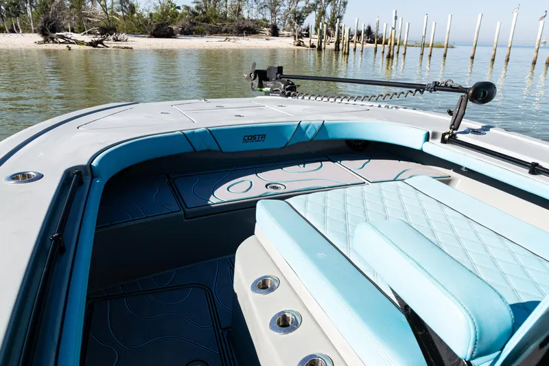  Yacht Photos Pics 2022 Costa Custom Boats 264 interior with blue seating, near a serene shoreline.