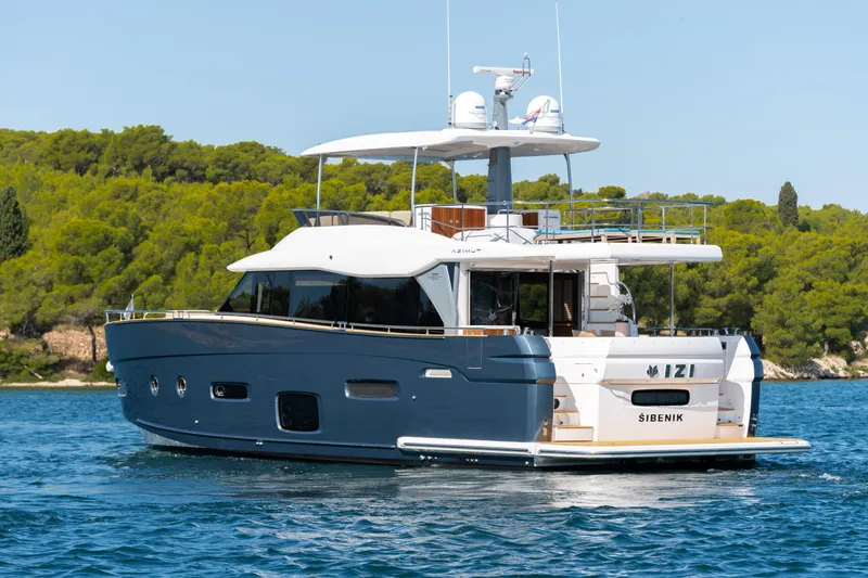 Izi Yacht Photos Pics Azimut Magellano 66 yacht, 2017 model, cruising on serene waters with lush greenery backdrop.