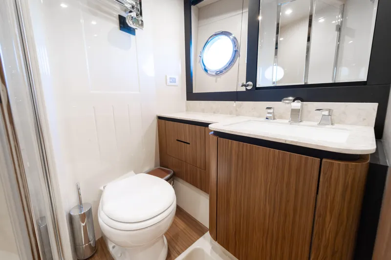 Izi Yacht Photos Pics Luxurious bathroom in 2017 Azimut Magellano 66 yacht with modern fixtures and porthole window.