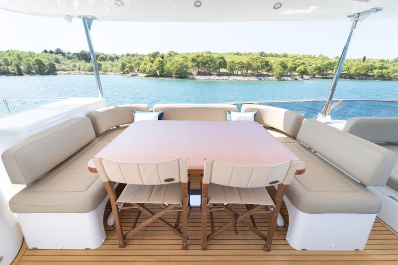 Izi Yacht Photos Pics Luxurious Azimut Magellano 66 yacht deck with elegant seating, overlooking serene waters and lush greenery.