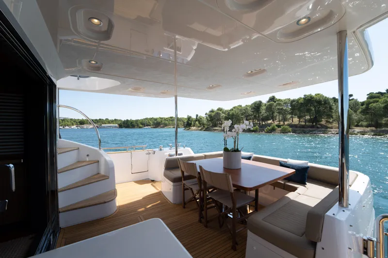 Izi Yacht Photos Pics Luxurious Azimut Magellano 66 yacht deck with dining area, overlooking serene waters and lush greenery.