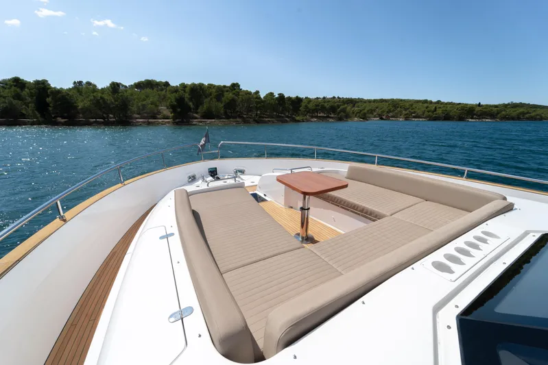 Izi Yacht Photos Pics Luxurious 2017 Azimut Magellano 66 yacht deck with sun loungers and table, overlooking serene waters.