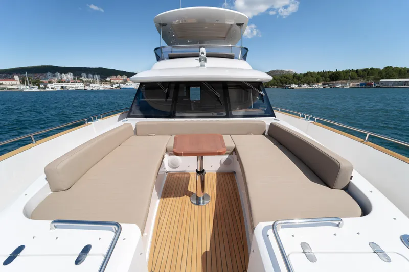 Izi Yacht Photos Pics 2017 Azimut Magellano 66 yacht with spacious deck seating and table, docked by the sea.