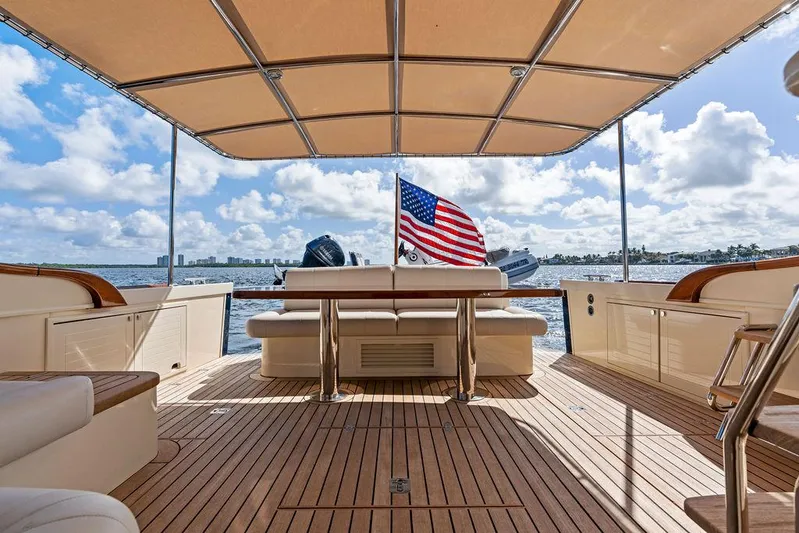 Tutto Bene Yacht Photos Pics 2018 Palm Beach Motor Yachts PB55 Flybridge, spacious deck with seating, American flag, ocean view.