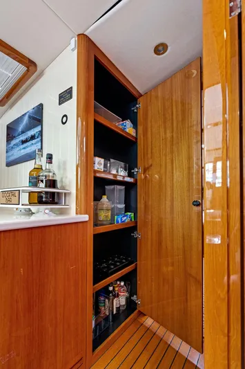 Tutto Bene Yacht Photos Pics 2018 Palm Beach Motor Yachts PB55 Flybridge interior with wooden cabinetry and stocked shelves.