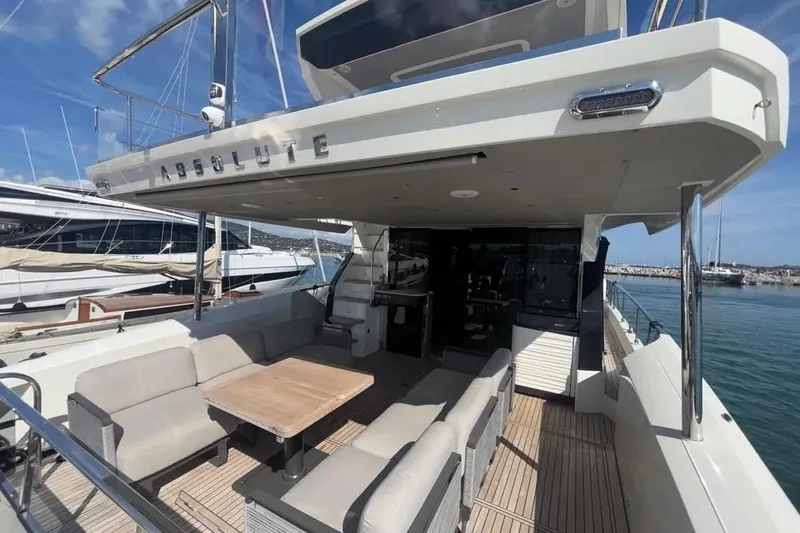  Yacht Photos Pics 2023 Absolute 60 Fly yacht deck with seating and table, docked at marina.