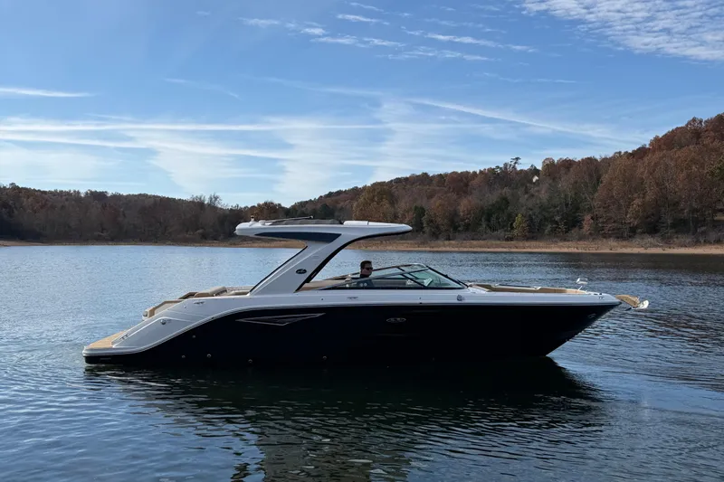  Yacht Photos Pics 2026 Sea Ray SLX 310 boat on a serene lake with wooded shoreline.