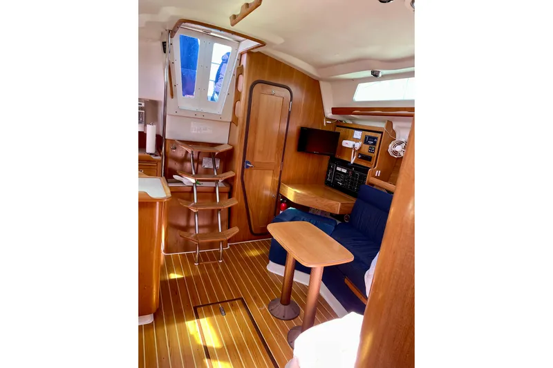 Quest Yacht Photos Pics Interior of 2004 Catalina 350 sailboat with wooden furnishings and blue seating.