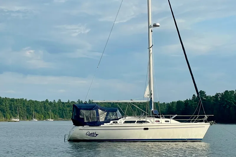 Quest Yacht Photos Pics 2004 Catalina 350 sailboat anchored on a serene lake with forested shoreline.