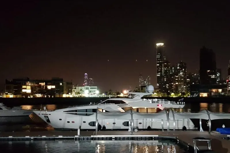 Sha Sha Sha IV Yacht Photos Pics Luxurious 2014 Custom Line 100 yacht docked at night with city skyline backdrop.