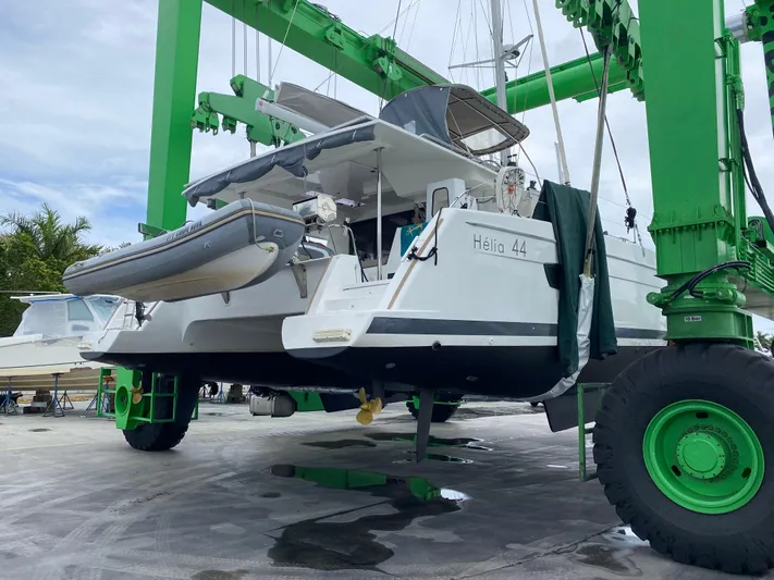 Carpe Aura Yacht Photos Pics 2018 Fountaine Pajot Helia 44 catamaran in dry dock, green lift, overcast sky.