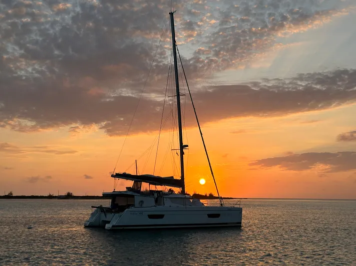 Carpe Aura Yacht Photos Pics Fountaine Pajot Helia 44 catamaran at sunset, 2018 model, on tranquil water.