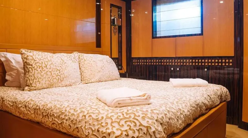  Yacht Photos Pics Luxurious bedroom interior on 2009 Mangusta 165 yacht with elegant bedding and warm wood paneling.