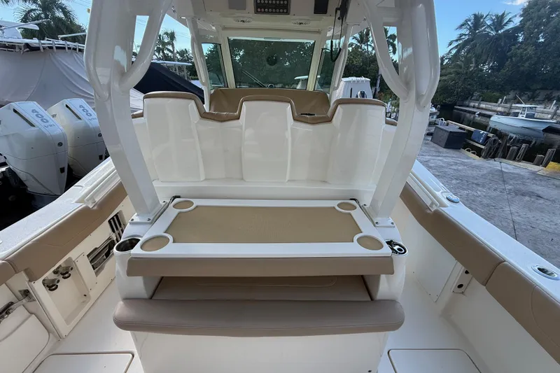  Yacht Photos Pics 2022 Scout 355 LXF boat interior with seating and cup holders, docked near palm trees.