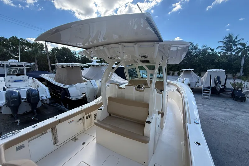  Yacht Photos Pics 2022 Scout 355 LXF boat with seating and canopy, docked under a blue sky.