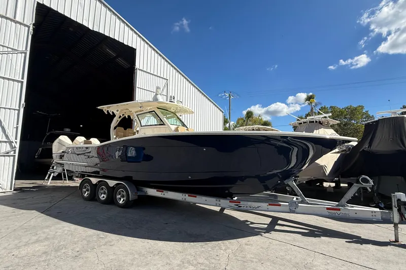  Yacht Photos Pics 2022 Scout 355 LXF boat on trailer outside storage facility under blue sky.