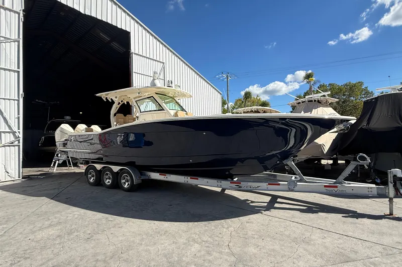  Yacht Photos Pics 2022 Scout 355 LXF boat on trailer outside storage facility under blue sky.