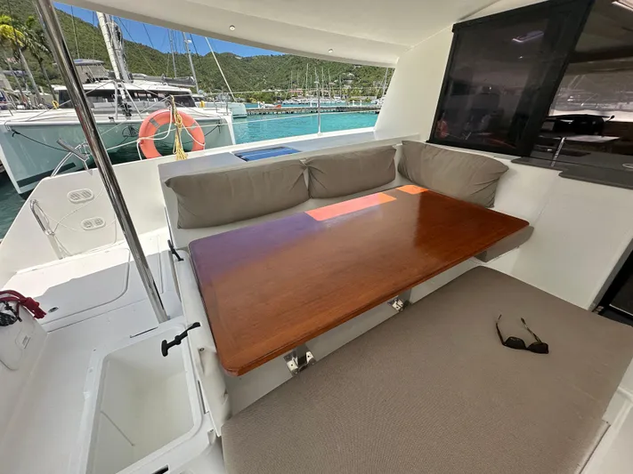 Goin' Coastal Yacht Photos Pics 2018 Fountaine Pajot Helia 44 Evolution yacht interior with cushioned seating and wooden table.