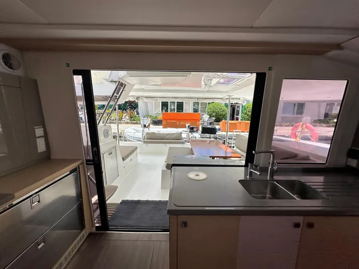 Goin' Coastal Yacht Photos Pics Interior view of 2018 Fountaine Pajot Helia 44 Evolution catamaran, featuring modern kitchen and outdoor seating.