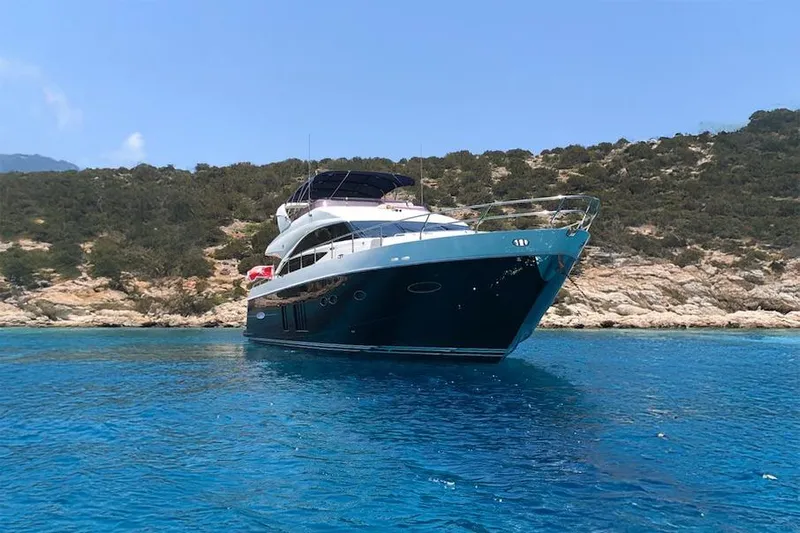  Yacht Photos Pics 2012 Princess 72 Motor Yacht anchored in clear blue water near rocky coastline.