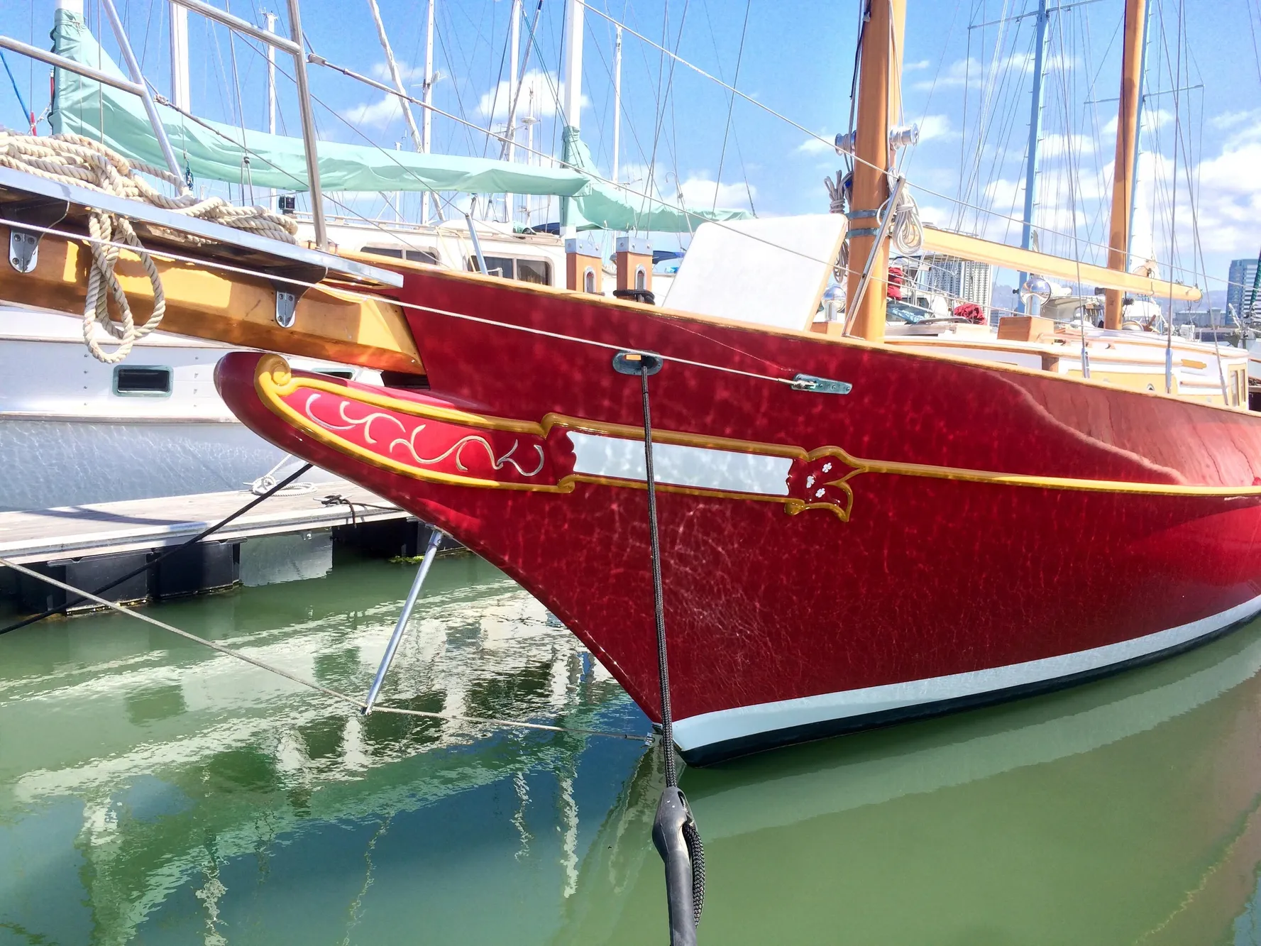 Red 1971 Formosa 41 sailboat docked in marina, featuring ornate detailing and wooden mast.