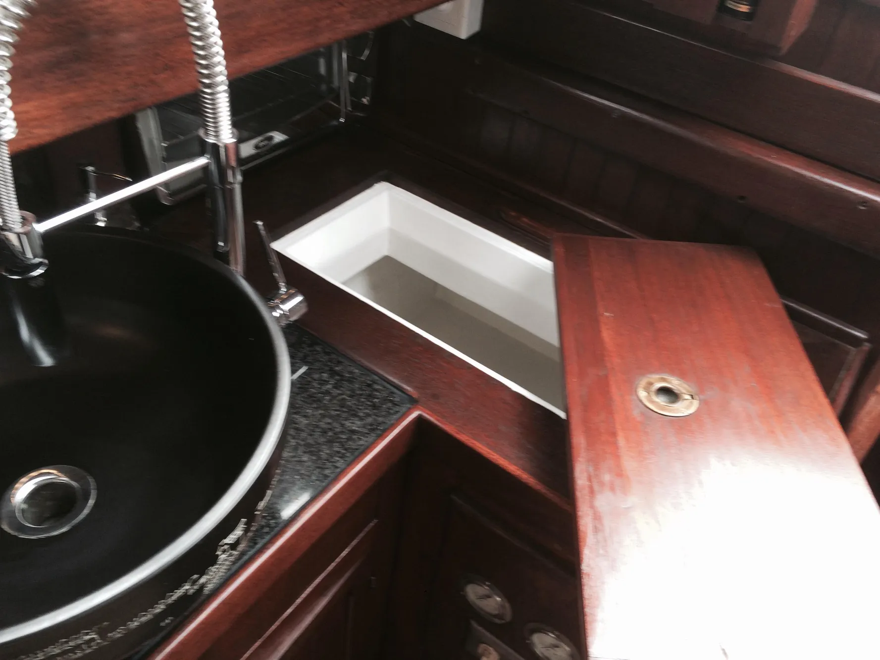 Interior of a 1971 Formosa 41 yacht with wooden cabinetry and a black sink.