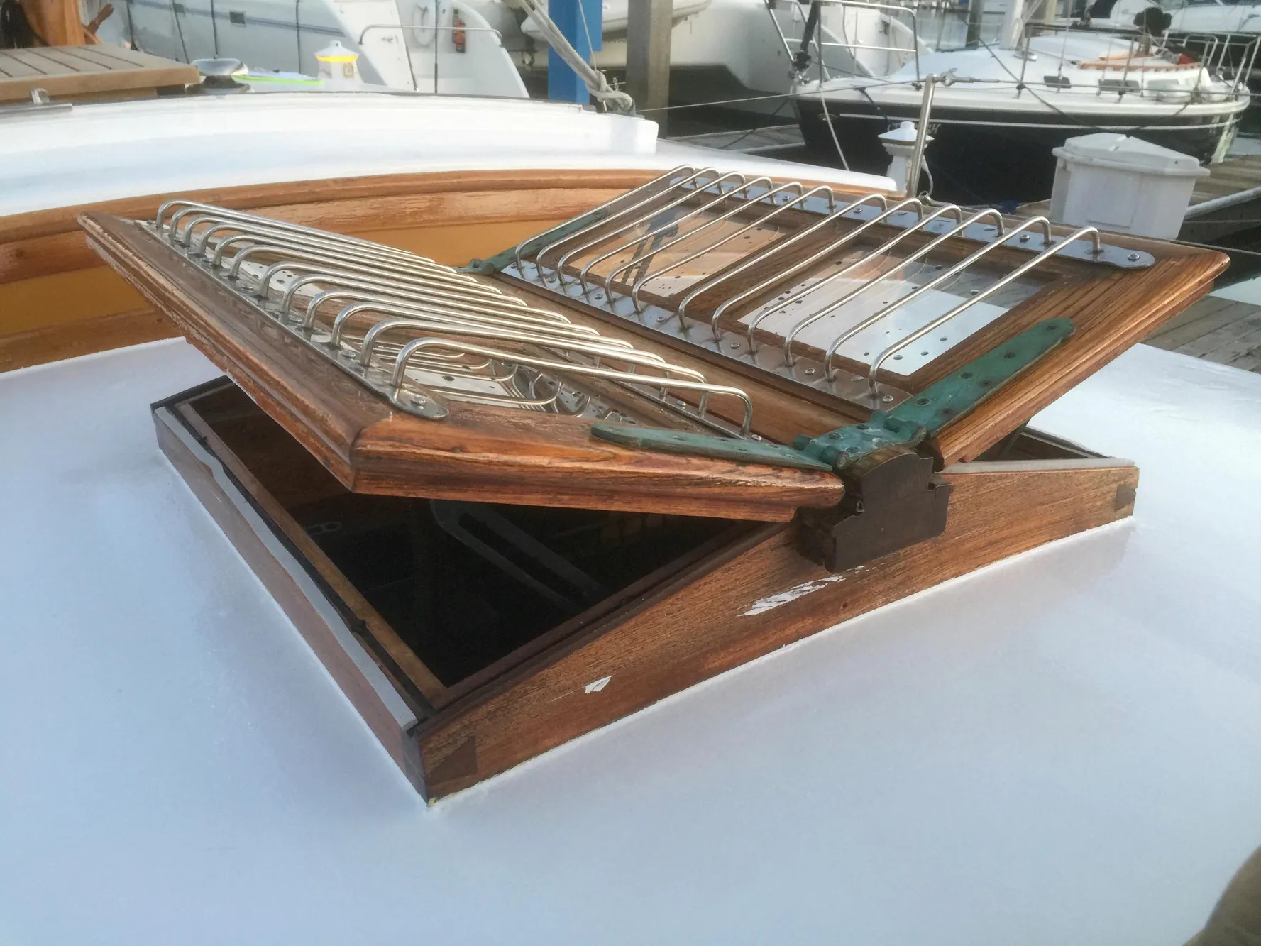 Wooden hatch on 1971 Formosa 41 sailboat, open with metal grill, docked in marina.