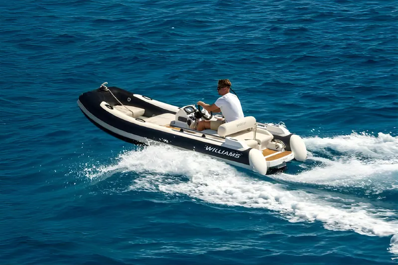  Yacht Photos Pics Man driving a Williams tender boat on clear blue ocean waters.