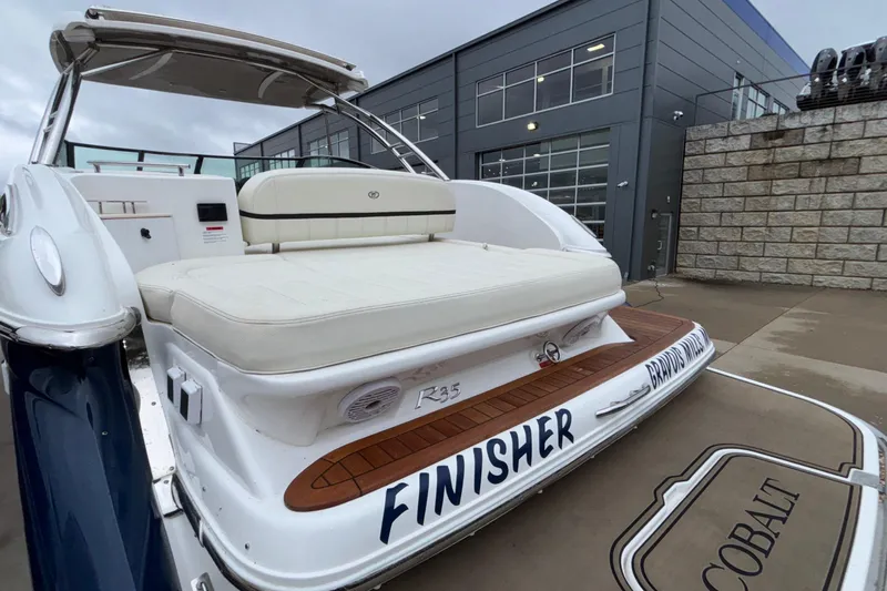  Yacht Photos Pics 2022 Cobalt R35 boat with white seating, docked near a modern building.