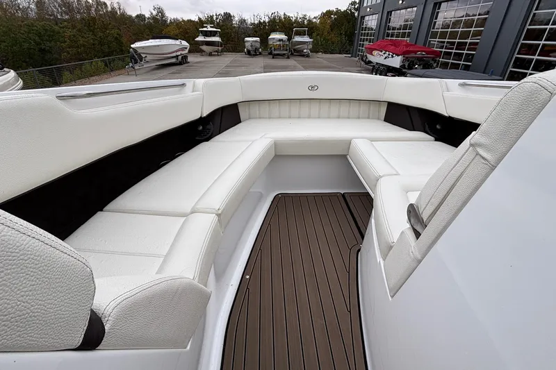  Yacht Photos Pics 2022 Cobalt R35 boat interior with white seating and wooden flooring, docked near other boats.